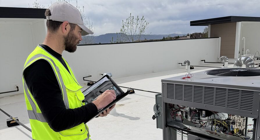 commercial HVAC technician looking at a rooftop AC unit