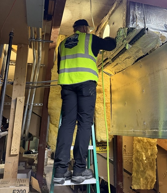 Man cleaning a commercial HVAC system on a ladder