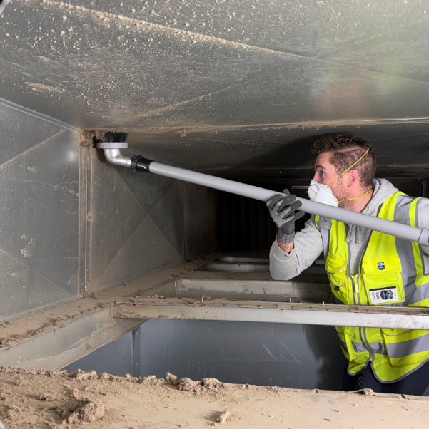 HVAC technician vacuuming commercial air ducts